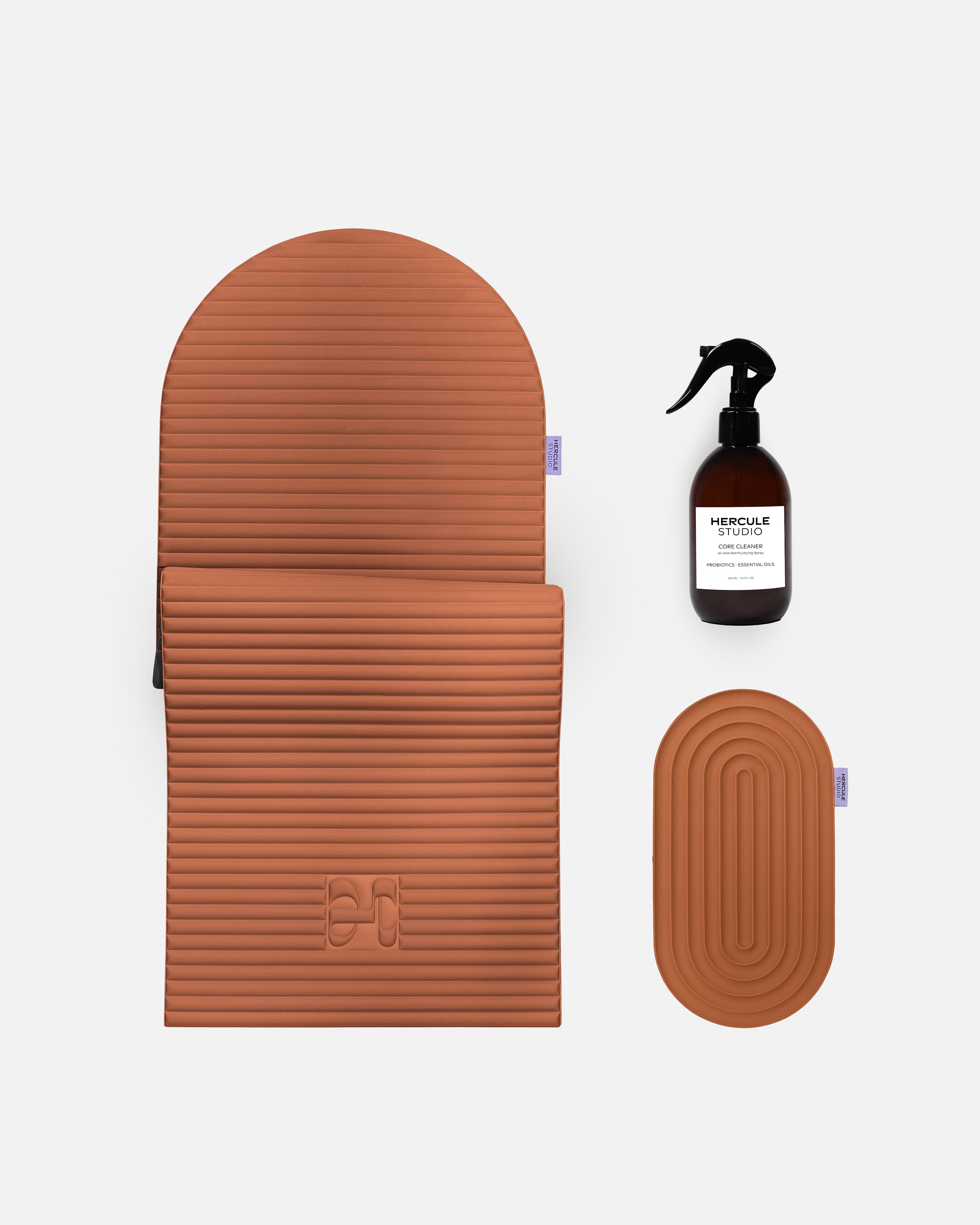 Set essentiel Hercule Studio terracotta comprenant tapis de sport Archy en forme d’arche, pad de confort Galé 3-en-1 pour genoux et coudes et spray assainissant pour tapis, ensemble Pilates et fitness design durable Made in France, packshot produits regroupés