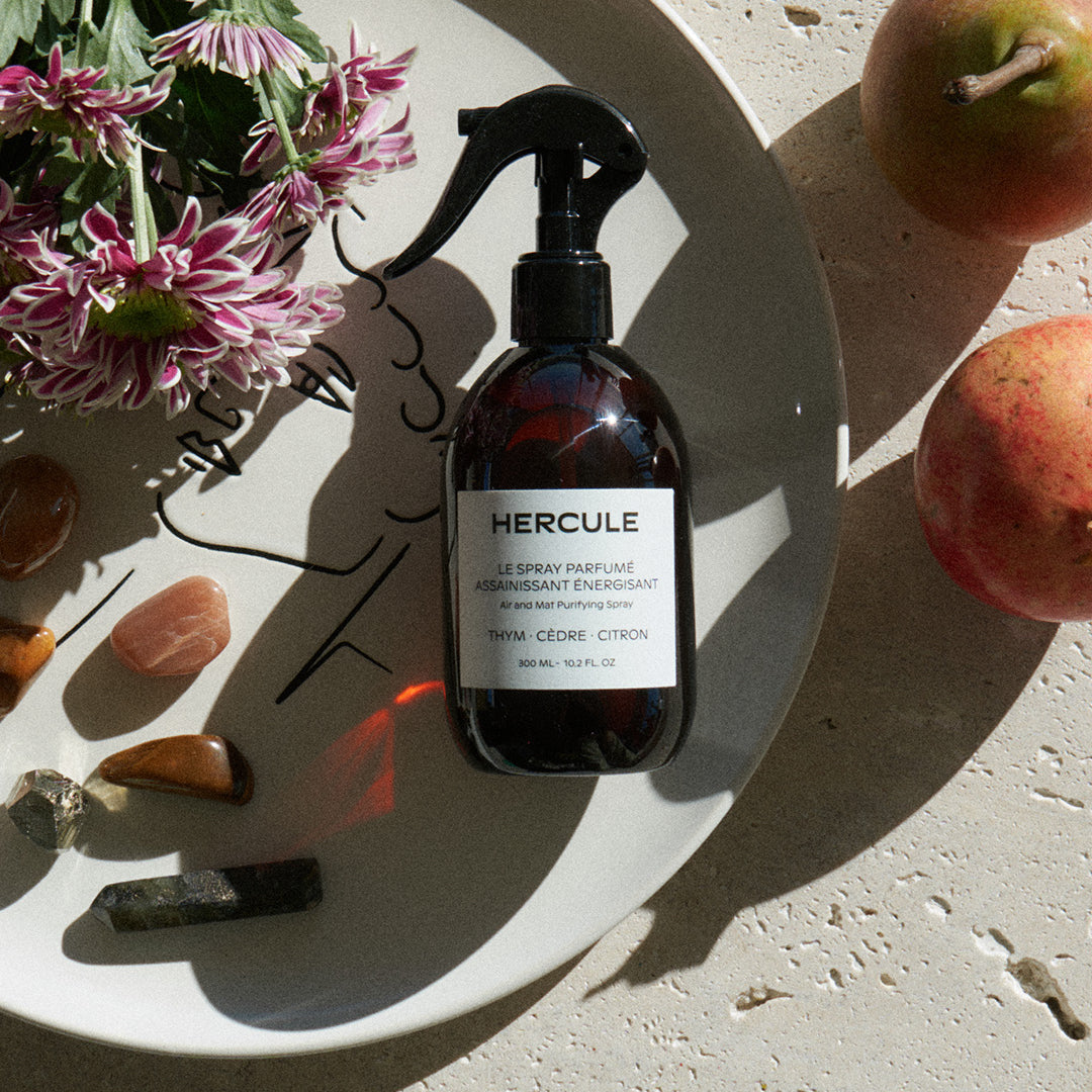 Spray pour assainir le tapis de sport et énergiser l'espace d'entraînement photo du produit sur une assiette et disposition de fleurs et pierres 